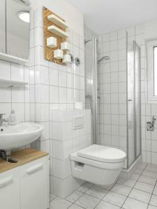 Baño blanco con aseo y lavamanos en Residenz am Yachthafen Schiffskieker, en Kirchdorf