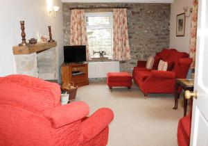 ein Wohnzimmer mit 2 roten Stühlen und einem TV in der Unterkunft Dalesmoor in Reeth