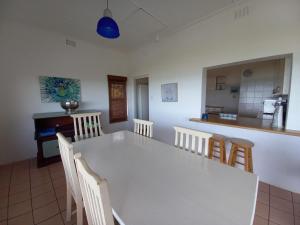 a dining room and kitchen with a white table and chairs at Ocean rush Seagull in Zinkwazi Beach