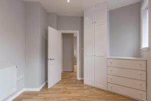an empty room with white cabinets and a hallway at Kensington Olympia Apartment, Breakfast in London