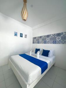 een witte slaapkamer met een blauw en wit bed bij Issa's Haven Resort in Look