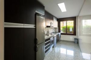 Apartamento Monte Laguna في فيلامورا: مطبخ كبير مع دواليب سوداء ونافذة