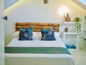 a bedroom with a bed with blue pillows at Little Diamond, Wooden Jungle House. Bathsheba. in Saint Joseph
