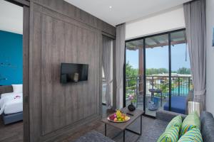 sala de estar con sofá y TV en la pared en 普吉岛-迈考海滩水疗度假村PL- Maikhaolak Beach Village, en Khao Lak