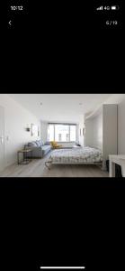 a white bedroom with a bed and a couch at Charmante studio op toplocatie aan Meir. in Antwerp