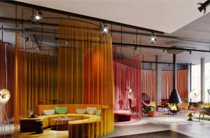 a living room with a yellow couch and red chairs at Moxy Outletcity Metzingen in Metzingen