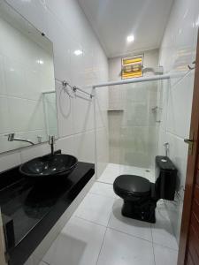 een badkamer met een zwart toilet en een wastafel bij Casa beira rio-mar in Barra de São Miguel