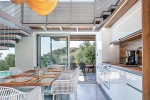 a kitchen with a long table with white chairs at New Stylish Villa Domus Rodia with private pool & BBQ, 4km from Plakias beach in Marioú