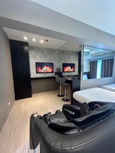 a bedroom with a bed and a couch and two monitors at Pasay Condotel with Massage Chair and PS4- Stellar Suites in Manila