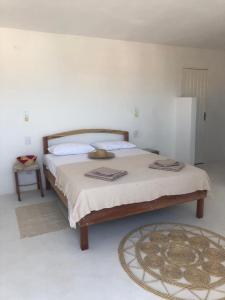 CASA BRANCA NA PRAIA في إيكابوي: غرفة نوم بسرير كبير وبجدران بيضاء