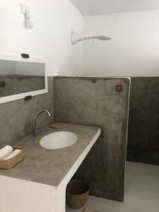 a bathroom with a sink and a light on the wall at CASA BRANCA NA PRAIA in Icapuí