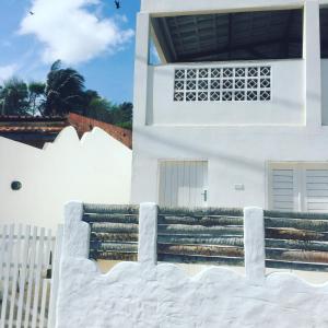 een wit huis met een trap en een hek bij CASA BRANCA NA PRAIA in Icapuí