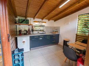 a kitchen with blue cabinets and a table at Kalinao - Bungalow chic en nature in Les Abymes