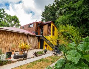 a house with a yellow staircase in a garden at Kalinao - Bungalow chic en nature in Les Abymes