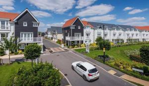 a white car driving down a street in a residential neighbourhood at Green Park 4 bed LUX with parking ,M4 Jct 11 in Reading
