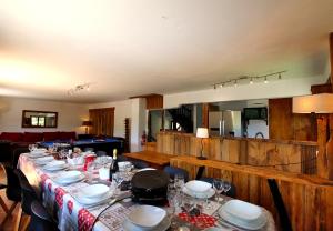 un comedor con una mesa con platos y copas de vino en Spacious Chalet 16/18 Guests w/Slope View, Jacuzzi et Sauna, en Montgenèvre