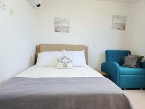 a bedroom with a bed and a blue chair at Apartamento para estrenar Ambar Roca - Bedviajes in Santa Marta