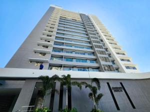 a tall building with palm trees in front of it at Apartamento para estrenar Ambar Roca - Bedviajes in Santa Marta