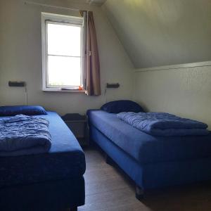 two beds in a small room with a window at De Vecht, 124 - centraal gelegen aan vijver in Gramsbergen