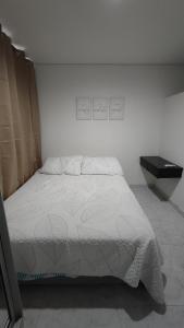a bedroom with a white bed with a sign on the wall at Cómodo apartaestudio en Cali para corta o larga estadía in Cali