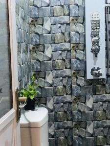 a bathroom with a stone wall behind a toilet at Ibeeza Motel in Dickwella