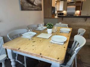 una mesa de madera con sillas, platos y copas de vino en Lakeview Lodge en Chichester