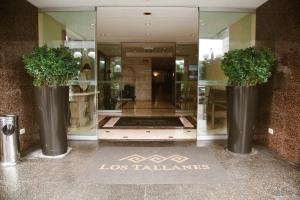 Los Tallanes Hotel & Suites في ليما: واجهة متجر مع مزهرين كبيرين مع نباتات فيها