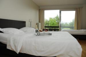 Schlafzimmer mit einem weißen Bett und einer Flasche Champagner in der Unterkunft Vakantiewoning La Cereza in Oudenaarde