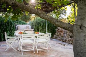 a table and chairs sitting under a tree at Sopra i Sassi - Villa & Trulli in Ostuni