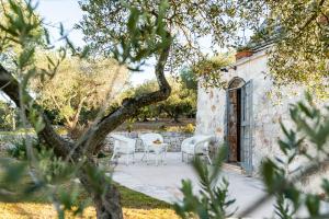 a patio with white chairs and a table at Sopra i Sassi - Villa & Trulli in Ostuni