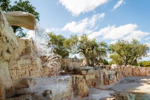 a fountain in a park with trees in the background at Sopra i Sassi - Villa & Trulli in Ostuni