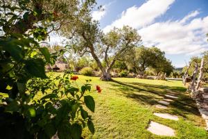 a garden with a tree and some flowers at Sopra i Sassi - Villa & Trulli in Ostuni