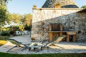 a patio with two chairs and a table and a stone fireplace at Sopra i Sassi - Villa & Trulli in Ostuni