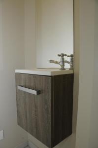 a bathroom with a sink and a wooden cabinet at Vakantiewoning La Cereza in Oudenaarde