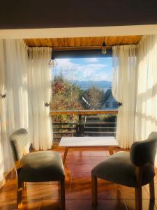 a living room with two chairs and a large window at Gross Guest House in San Carlos de Bariloche