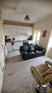 a living room with a black couch and a kitchen at Apartment 1, Regent Street in Bagenalstown