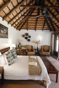 a bedroom with a large bed and two chairs at Duma Manzi Eco Lodge & Spa in Richmond