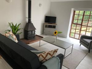 ein Wohnzimmer mit einem Sofa und einem Herd in der Unterkunft Light & Airy Vaulted Barn Conversion with a View in Sampford Arundel