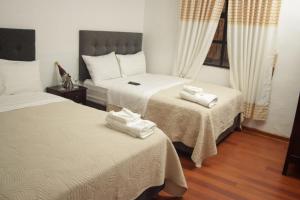 a bedroom with two beds with white sheets at Casona Valdelirios Hotel in Ayacucho