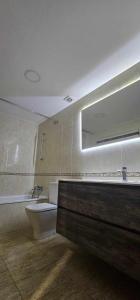 een badkamer met een wastafel, een toilet en een spiegel bij Apartamento Laia con máquina recreativa in Ribes de Freser