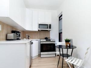 een keuken met witte kasten en een tafel met stoelen bij Stunning 3BR Apartment in NYC! in New York