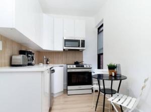 a kitchen with white cabinets and a table with chairs at Stunning 3BR Apartment in NYC! in New York