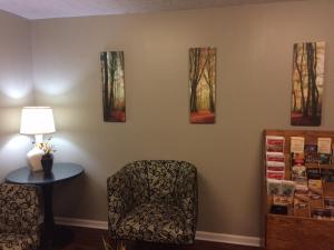 una habitación con una silla y pinturas en la pared en Motel M Lewisburg en Lewisburg