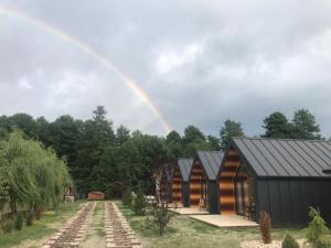 a rainbow in the sky above a house at Pastravaria Zavoi in Valea Danului