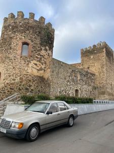 un coche blanco estacionado frente a un castillo en Alojamiento Orellana, en Orellana la Vieja