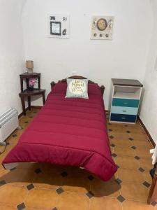1 cama grande de color rojo en una habitación con suelo en Alojamiento Orellana, en Orellana la Vieja