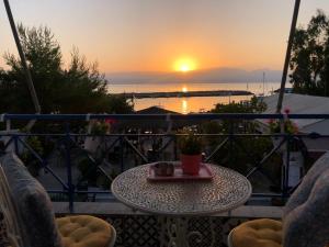 a table on a balcony with a view of the sunset at Urszula's apartment - apartments by the sea in Agios Andreas