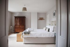 1 dormitorio con cama blanca y tocador de madera en Glebe House en Barford Saint Martin