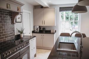 a kitchen with white cabinets and a sink at Glebe House in Barford Saint Martin