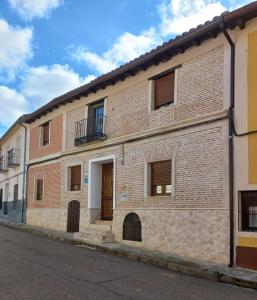 un edificio in mattoni con porta e balcone di Casa Calderón de Medina lV a Siete Iglesias de Trabancos